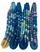 Four pairs of hand-knit patterned socks arranged vertically side-by-side on a white background. The socks feature intricate Fair Isle style patterns in shades of blue, teal, yellow, red, and gray, with solid-colored toes and heels.