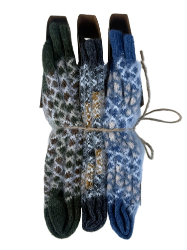 Three pairs of folded knit gloves bundled together with twine, displayed against a white background. The gloves feature intricate Fair Isle patterns in dark green, charcoal gray, and slate blue.