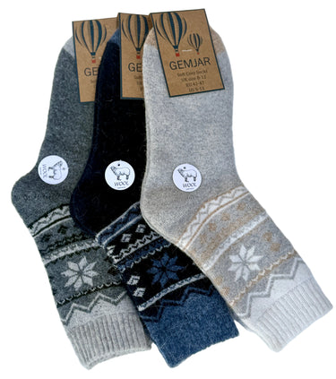 Three pairs of patterned knit socks arranged in a fan shape on a white background, each with a paper tag. The socks are in grey, beige, and navy, with traditional Nordic/Snowflake patterns and ribbed cuffs.