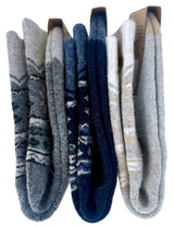 Three pairs of folded knit socks displayed side by side on a white background. The left pair is heather gray with dark gray geometric patterns, the middle pair is navy blue with white geometric patterns, and the right pair is light gray with beige.